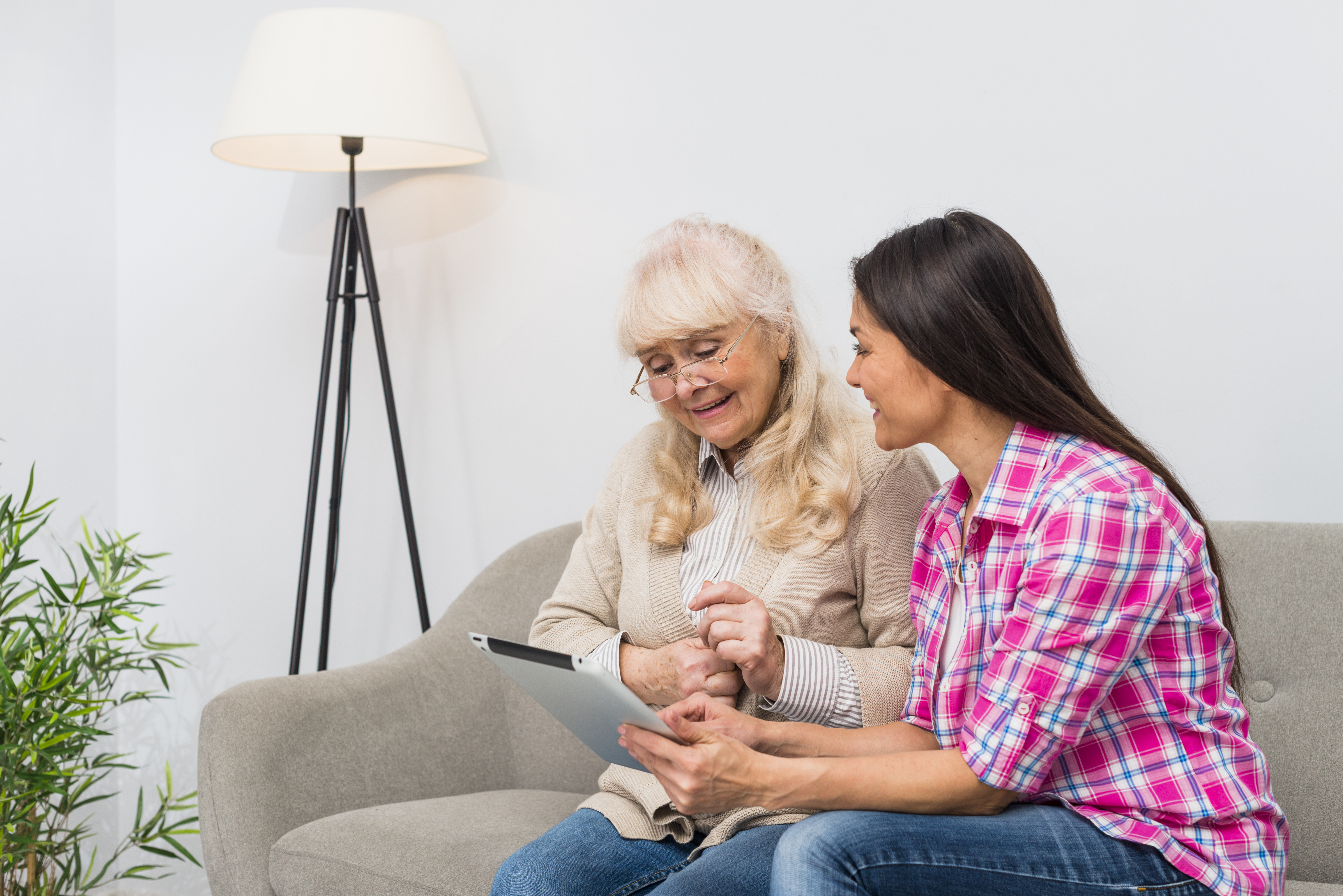 silly-senior-mother-and-her-daughter-using-digital-tablet-while-sitting-on-sofa